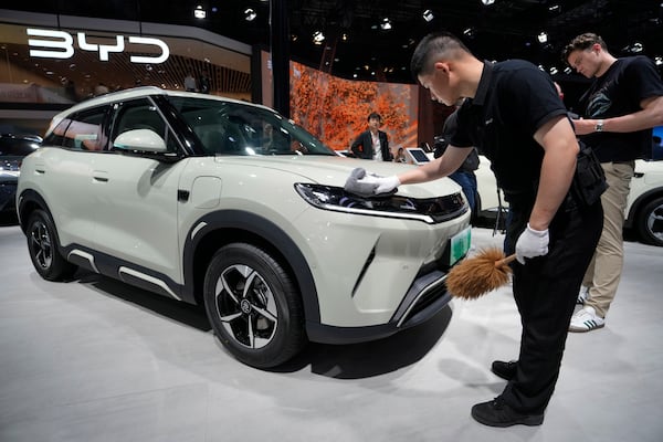 A worker polishes the surface of a BYD car during the Shanghai auto show on Wednesday, April 23, 2025. (AP Photo/Ng Han Guan)