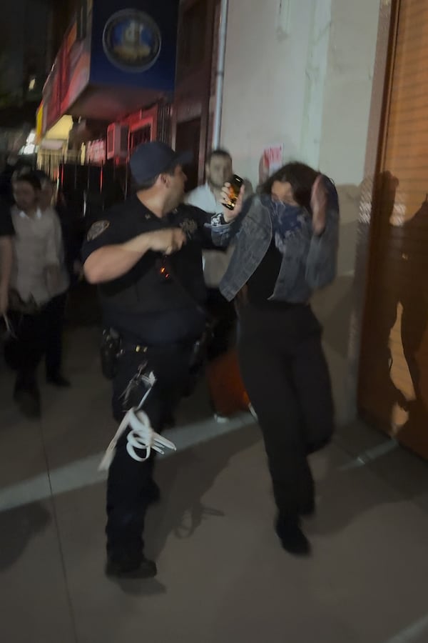 This image taken from video shows a woman and a police officer as they are pursued by a crowd of men in the Crown Heights section of Brooklyn, N.Y., on Thursday, April 24, 2025. (AP Photo)