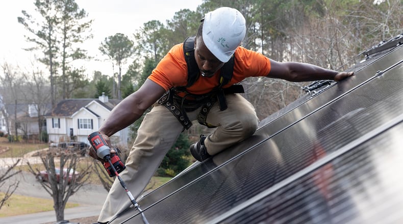 Mike Harris, an installer for Creative Solar USA, installs solar panels on a home in Ball Ground, Ga., on December 17, 2021.