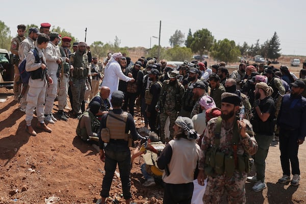 Bedouin fighters, right, gather as Syrian government security forces, left, block them from entering Sweida province, in Busra al-Harir village, southern Syria, Sunday, July 20, 2025. (AP Photo/Ghaith Alsayed)