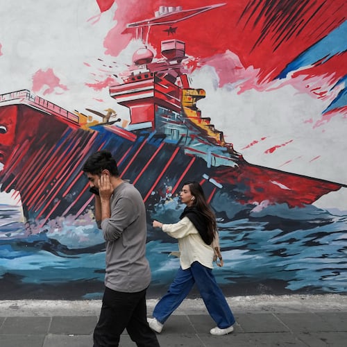 People walk past a mural depicting a U.S. aircraft carrier under missile attack in downtown Tehran, Iran, Sunday, May 17, 2026. (AP Photo/Vahid Salemi)