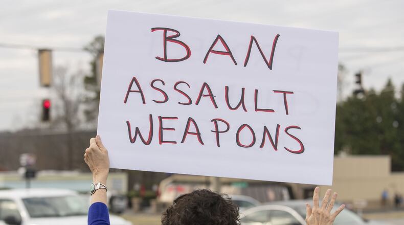 A woman holds a sign in during a protest against the National Rifle Association along Alabama Road NE in Woodstock, Tuesday, February 20, 2018. ALYSSA POINTER/ALYSSA.POINTER@AJC.COM