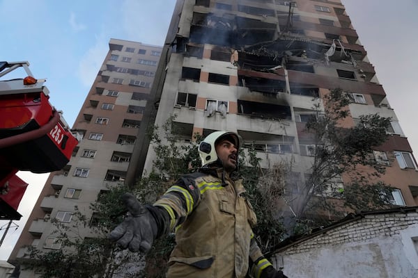 A firefighter calls out his colleagues at the scene of an explosion in a residence compound in northern Tehran, Iran, Friday, June 13, 2025. (AP Photo/Vahid Salemi)