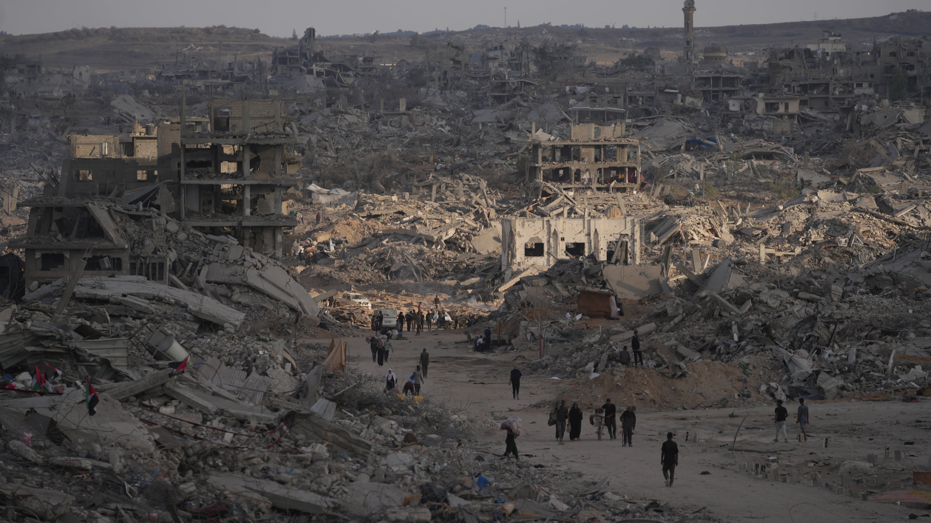 Palestinians walk among destroyed buildings in Gaza City, Sunday, Oct. 12, 2025, after Israel and Hamas agreed to a pause in their war and the release of the remaining hostages. (AP Photo/Jehad Alshrafi)