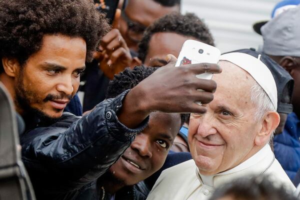 FILE - Pope Francis poses for selfie photos with migrants at a regional migrant center in Bologna, Italy, Oct. 1, 2017. (AP Photo/Luca Bruno, File)