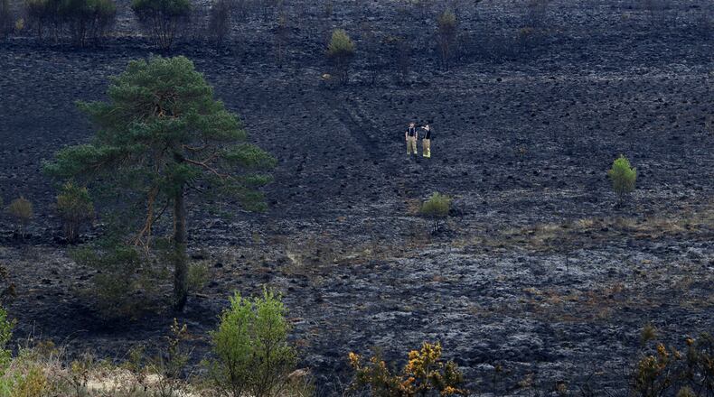 Firefighters check the area after a fire at Ashdown Forest, southern England, Monday April 29, 2019. Fire services attended the scene Sunday evening to tackle the blaze.