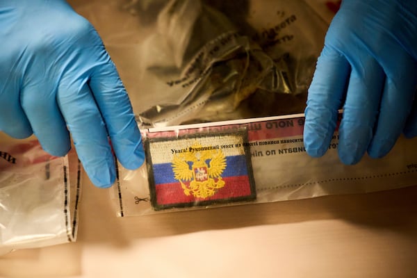 A police expert shows chevron of Russian soldier killed in the Russia-Ukraine war during the Ukrainian Interior Minister Ihor Klymenko's briefing on repatriation of fallen solders in Kyiv, Ukraine, Monday, June 23, 2025. (AP Photo/Efrem Lukatsky)
