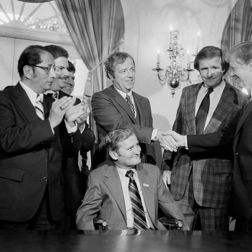 FILE - President Jimmy Carter, right, shakes hands with the Michigan delegation, in Washington, April 24, 1980, who were present for the signing by Carter of a bill that would enable Volkswagen to operate an auto assembly plant in a Detroit suburb. Sen. Don Riegle, D-Mich., next to Carter, and Michigan Senate Majority Leader William Faust seated center, look on. (AP Photo, File)