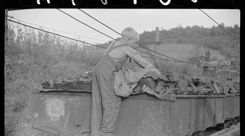In this historic Library of Congress photo, a miner's son swipes coal from coal cars for home use in West Virginia.