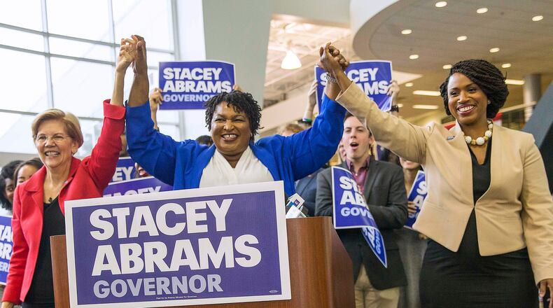 Democratic gubernatorial candidate Stacey Abrams links hands with U.S. Sen. Elizabeth Warren of Massachusetts (left) and Democratic congressional candidate Ayanna Pressley (right) during a rally at Clayton State University in Morrow on Tuesday. ALYSSA POINTER/ALYSSA.POINTER@AJC.COM
