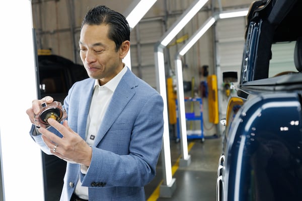 Chau Nguyen, founder and CEO of Vintage Modern, holds a chrome gas cap that his company ships from Detroit to install on its vehicles. He showed it during a tour of his company's Buford headquarters on June 26, 2026. (Estela Muñoz/AJC)