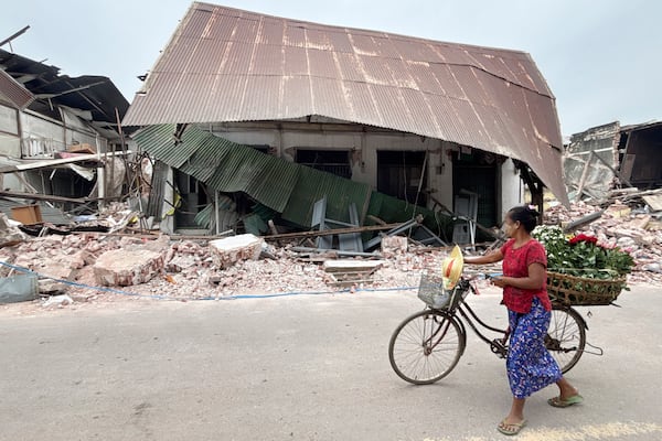 A local woman pushing her bicycle walks past a damaged building in the aftermath of an earthquake on March 28, in Naypyitaw, Myanmar, Monday, April 7, 2025. (AP Photo)