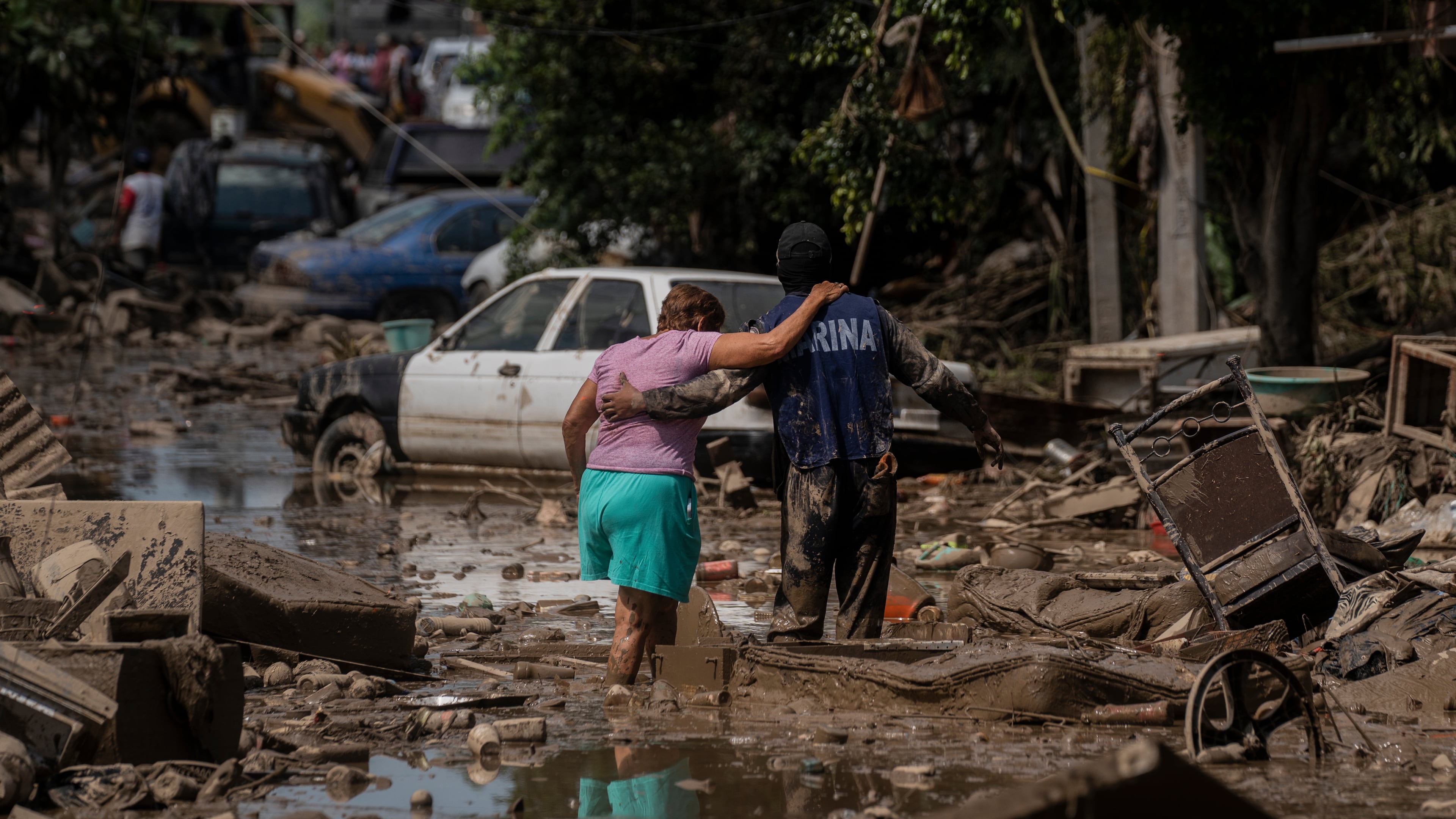 A Marine helps a woman cross a flooded street in Poza Rica, Veracruz state, Mexico, Sunday, Oct. 12, 2025. (AP Photo/Felix Marquez)