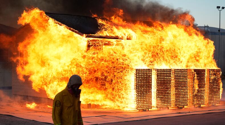 A wildfire researcher walks in front of an accessory dwelling unit burning during an experiment at the Institute for Business & Home Safety center on Thursday, April 16, 2026, in Richburg, S.C. (AP Photo/Erik Verduzco)