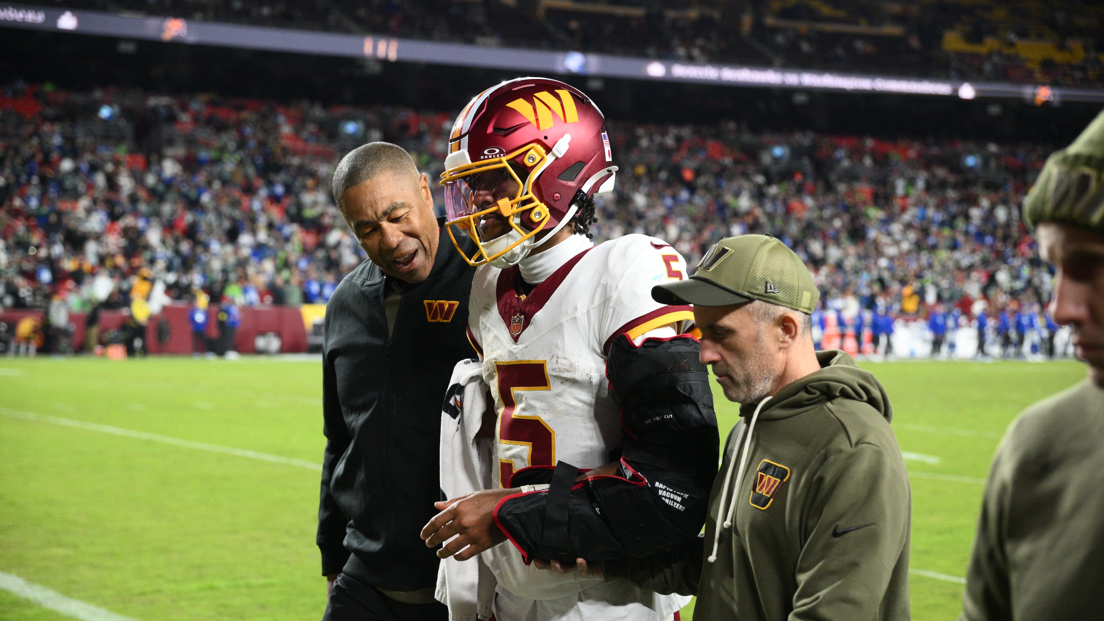 Washington Commanders quarterback Jayden Daniels (5) is helped off the field after he injuring his arm during a play in the second half of an NFL football game, Sunday, Nov. 2, 2025, in Landover, Md. (AP Photo/Nick Wass)