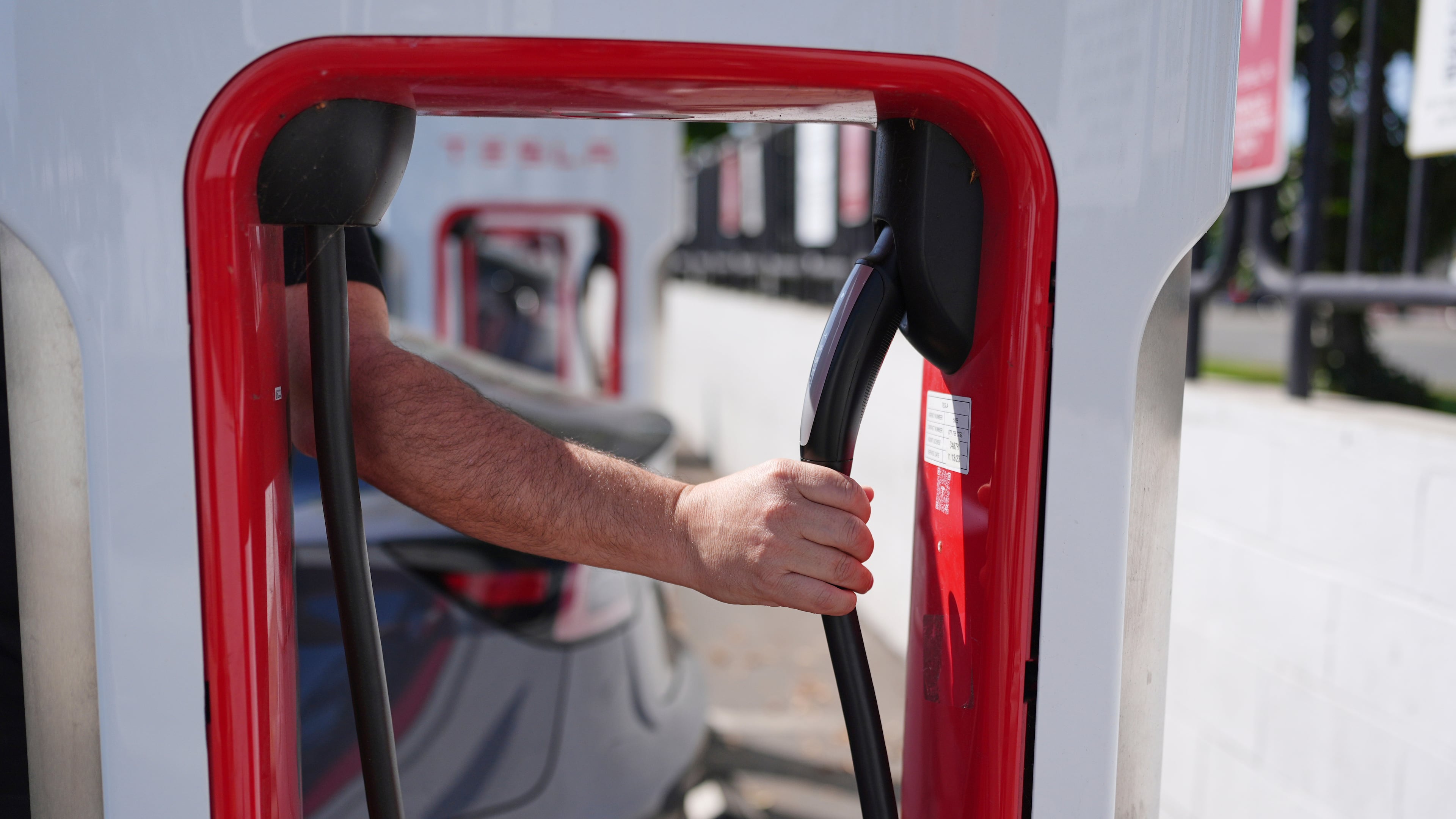 FILE - A person reaches to plug in an electric vehicle at a charging station May 22, 2025, in the City of Commerce, Calif. (AP Photo/Jae C. Hong, File)