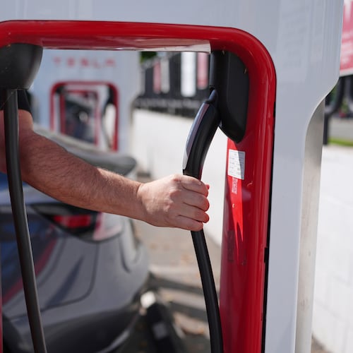 FILE - A person reaches to plug in an electric vehicle at a charging station May 22, 2025, in the City of Commerce, Calif. (AP Photo/Jae C. Hong, File)