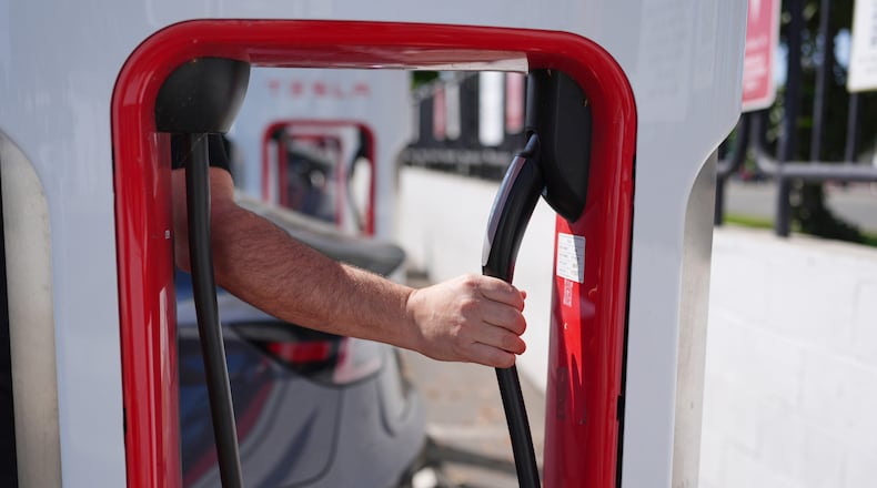 FILE - A person reaches to plug in an electric vehicle at a charging station May 22, 2025, in the City of Commerce, Calif. (AP Photo/Jae C. Hong, File)