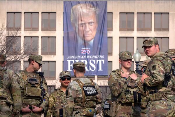National Guard members gather near a large portrait of President Donald Trump on the Labor Department headquarters before the body of Metropolitan Police Department officer Terry Bennett is driven past the Capitol, Jan. 8, 2026, in Washington. (Mark Schiefelbein/AP)