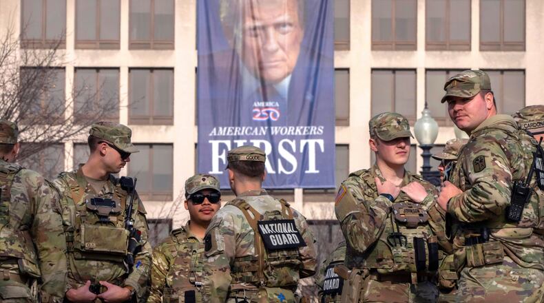 FILE - National Guard members gather near a large portrait of President Donald Trump on the Labor Department headquarters before the body of Metropolitan Police Department officer Terry Bennett is driven past the Capitol, Jan. 8, 2026, in Washington. (AP Photo/Mark Schiefelbein, File)