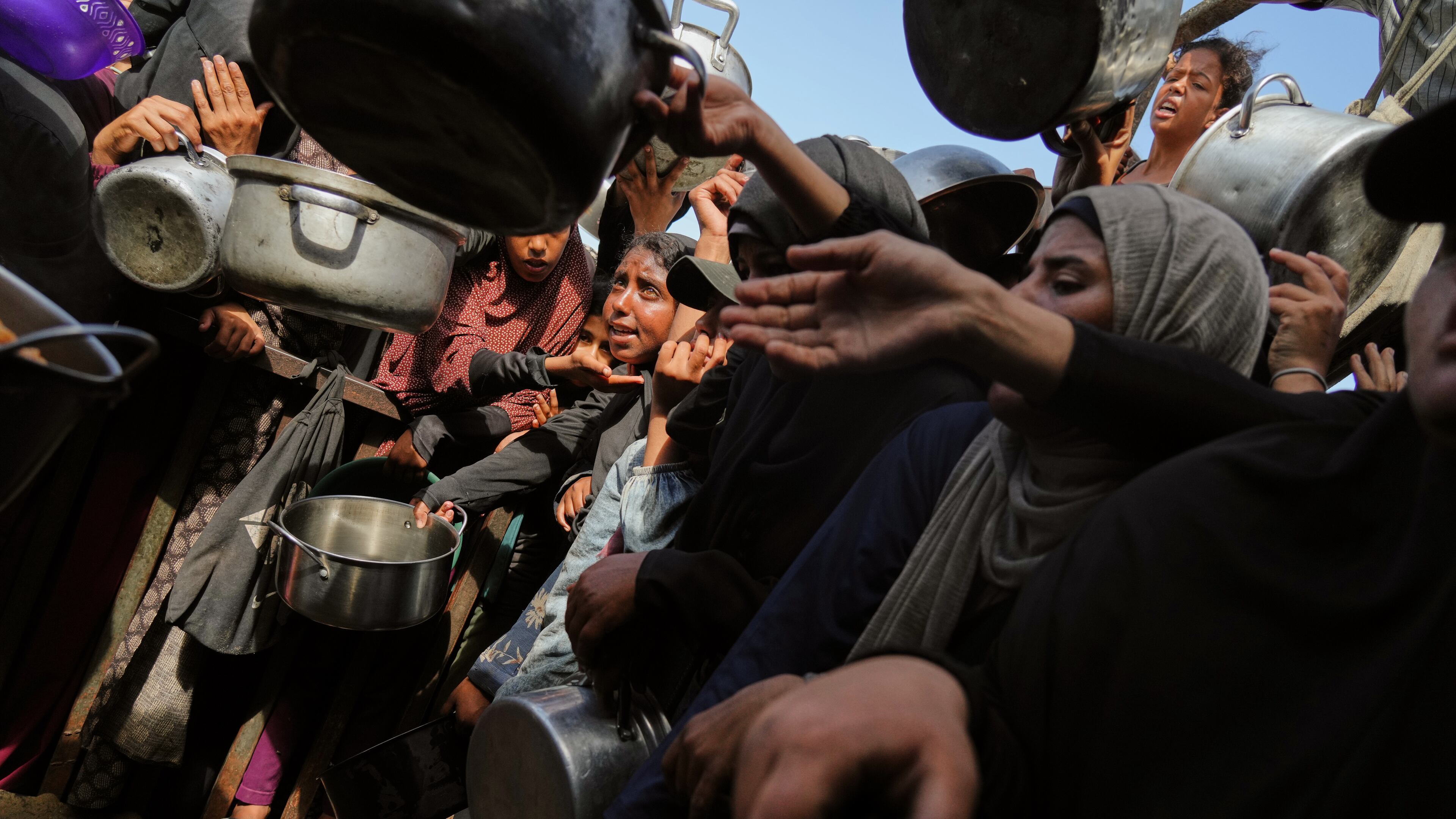 Palestinians struggle to get donated food at a community kitchen in Khan Younis, southern Gaza Strip, Sunday, Oct. 5, 2025. (AP Photo/Jehad Alshrafi)