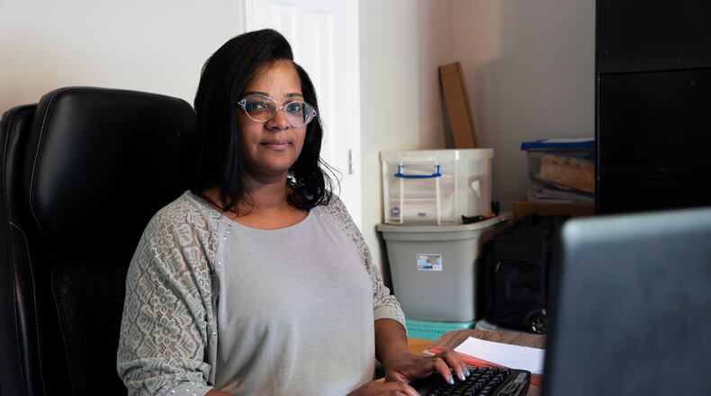 Tiesha Foreman poses for a portrait while checking her email at her home office in Douglasville, Georgia on Tuesday, April 16, 2024. Her job is harder now because, her lawyers say, she has become the victim of an insurance scam that has cost her thousands of dollars. She and her family have not gotten health care they needed because their insurance coverage was switched out from under them without their knowledge, she says. And not just once, but over and over. (PHOTO by Olivia Bowdoin for the AJC).