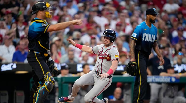Atlanta Braves' Lane Thomas, center, scores past Philadelphia Phillies catcher J.T. Realmuto, left, and pitcher Cristopher Sánchez on a single by Austin Riley during the second inning of a baseball game Friday, Sept. 4, 2026, in Philadelphia. (AP Photo/Matt Slocum)