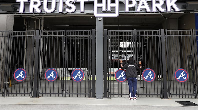 During a visit to the Battery Atlanta baseball fan Dwayne Jones pauses to take a look through the gates at the Atlanta Braves newly renamed Truist Park after new signage has been installed waiting for the delayed start of baseball season in the wake of the coronavirus on Monday, March 16, 2020, in Atlanta.   Curtis Compton ccompton@ajc.com