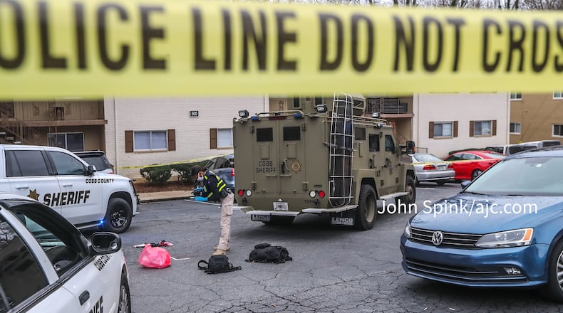 A GBI agent photographs evidence in the parking lot of the Concord Chase Apartments after a shooting.