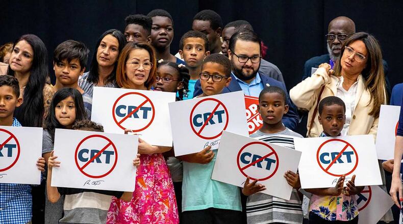 Schoolchildren holding signs against the concept of critical race theory stand on stage as Florida Gov. Ron DeSantis addresses the crowd before signing House Bill 7, titled the "Individual Freedom" bill but also dubbed the “Stop WOKE Act,” during a news conference at Mater Academy Charter Middle/High School in Hialeah Gardens, Fla., on April 22, 2022. (Daniel A. Varela/Miami Herald/TNS)