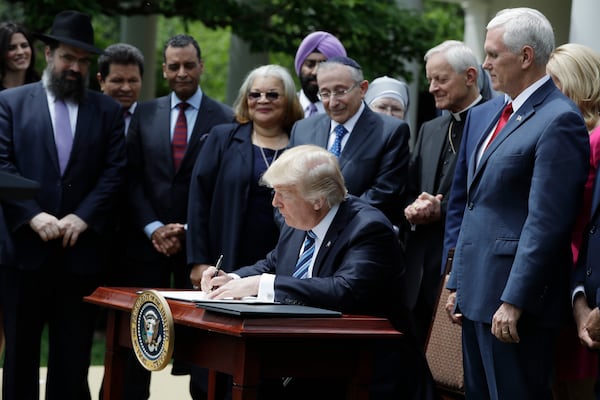 President Donald Trump signs an executive order in the Rose Garden asking the IRS to use "maximum enforcement discretion" over the regulation known as the Johnson Amendment. (Evan Vucci/AJC)
