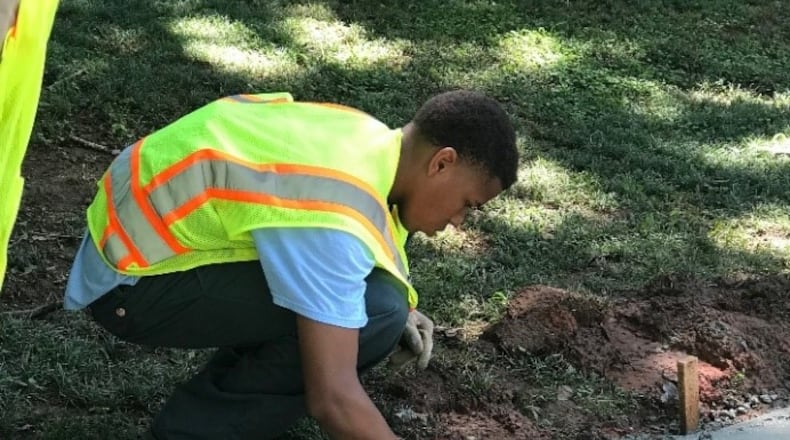 A youth helps to repair a sidewalk during last year’s DeKalb Works Summer Youth Employment Program. CONTRIBUTED