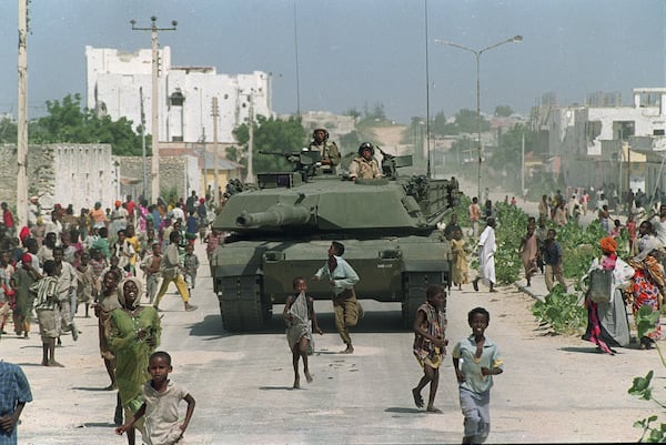 Somali children run alongside a U.S. Marine M-1 Abrams tank during an armored patrol in north Mogadishu, Somalia. (Mark Duncan/AP 1993)