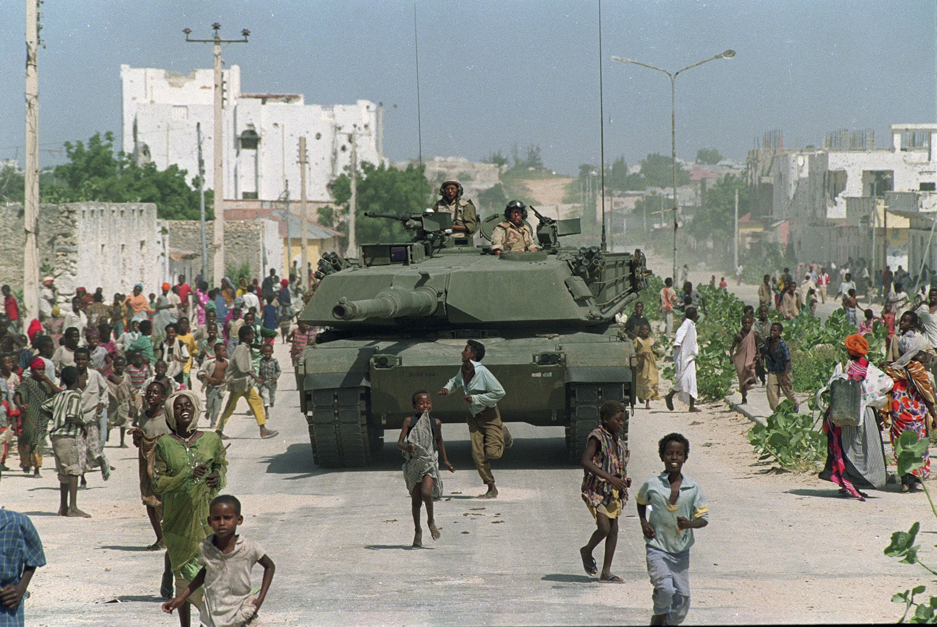 Somali children run alongside a U.S. Marine M-1 Abrams tank during an armored patrol in north Mogadishu, Somalia. (Mark Duncan/AP 1993)