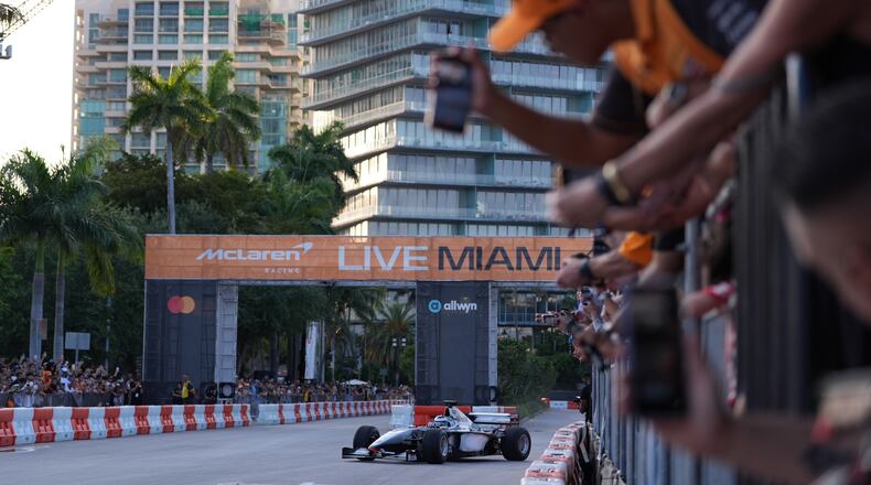 Fans watch as former Brazilian racing driver Bruno Senna steers an MP4/6 during a fan event showcasing past McLaren race cars ahead of the Formula One Miami Grand Prix auto race, Wednesday, April 29, 2026, in the Coconut Grove area of Miami. (AP Photo/Rebecca Blackwell)