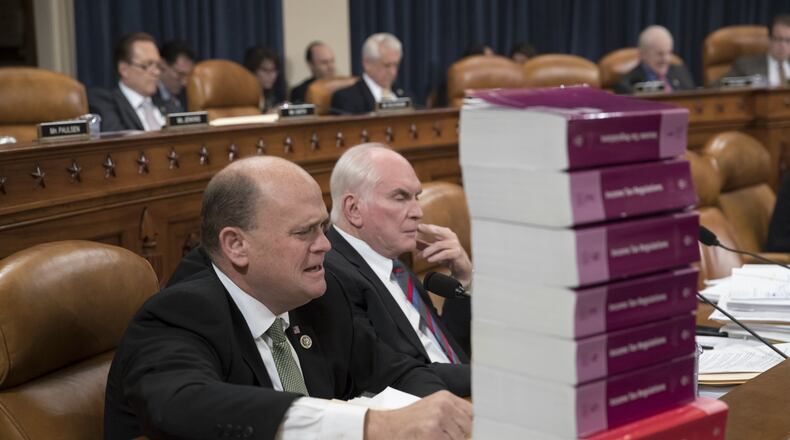 Seated behind a stack of IRS and tax volumes, Rep. Tom Reed, R-N.Y., left, joined by Rep. Mike Kelly, R-Pa., appeals to his Democratic opposition during debate on recent amendments to the House Republican tax reform plan, on Capitol Hill in Washington. (AP Photo/J. Scott Applewhite)
