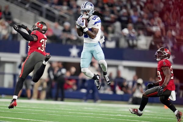 FILE - Dallas Cowboys wide receiver CeeDee Lamb (88) catches a pass between Tampa Bay Buccaneers cornerback Jamel Dean (35) and Christian Izien (29) in the first half of an NFL football game in Arlington, Texas, Sunday, Dec. 22, 2024. (AP Photo/Julio Cortez, File)