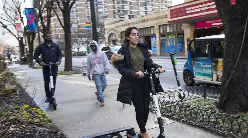 A woman rides a Bird scooter along the sidewalk on Peachtree Street in Atlanta’s Midtown community, Friday, Jan. 4, 2019. (ALYSSA POINTER/ALYSSA.POINTER@AJC.COM)