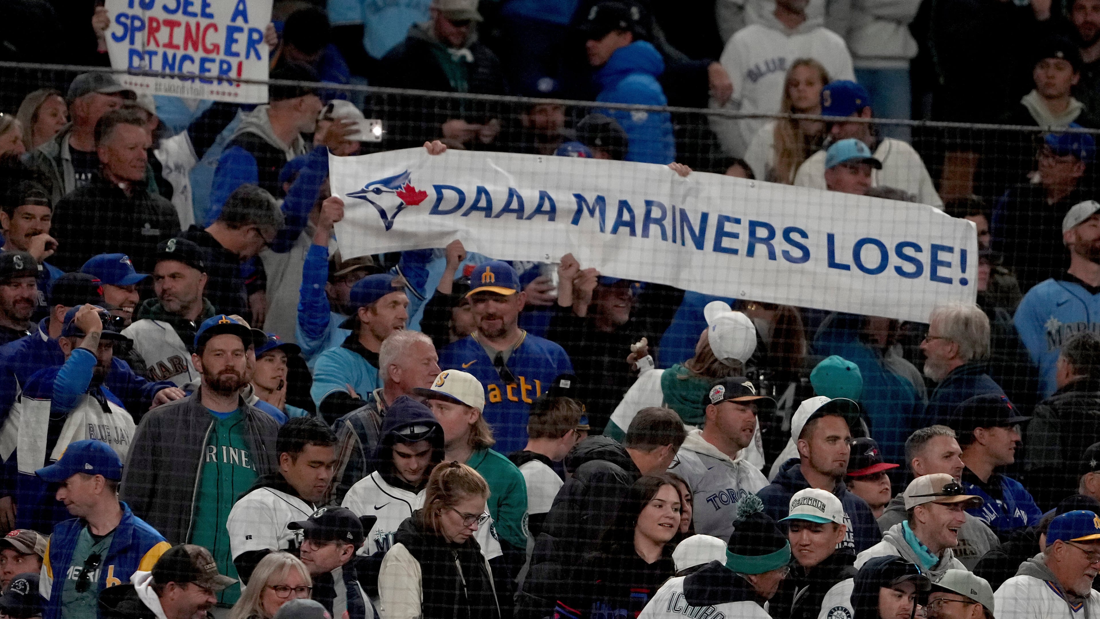 Toronto Blue Jays fans hold signs during the eighth inning in Game 3 of baseball's American League Championship Series against the Seattle Mariners, Wednesday, Oct. 15, 2025, in Seattle. (AP Photo/Lindsey Wasson)