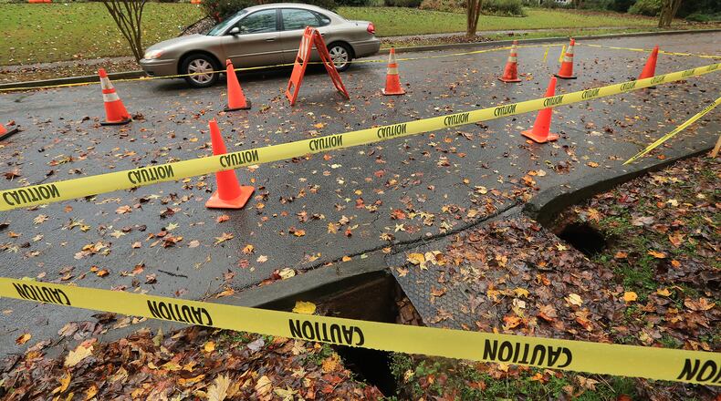 A motorist passes by a sinkhole forming on Berkeley Road around a storm drain in DeKalb County after heavy rains on Nov. 8, 2015 in Avondale Estates. Curtis Compton / ccompton@ajc.com