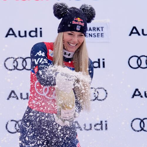 United States' Lindsey Vonn sprays sparkling wine as she celebrates on podium after winning an alpine ski, women's World Cup downhill, in Zauchensee, Austria, Saturday, Jan. 10, 2026. (AP Photo/Giovanni Auletta)