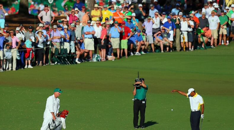 Tiger Woods takes his infamous drop on No. 15 in 2013, for which his was later penalized. (Curtis Compton/ccompton@ajc.com)