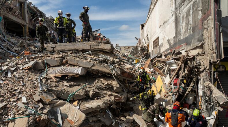 Rescuers carry the body of a victim from the rubble four days after after an earthquake hit Pereira, Colombia, Friday, Aug. 14, 2026. (AP Photo/Brandon Pinto)