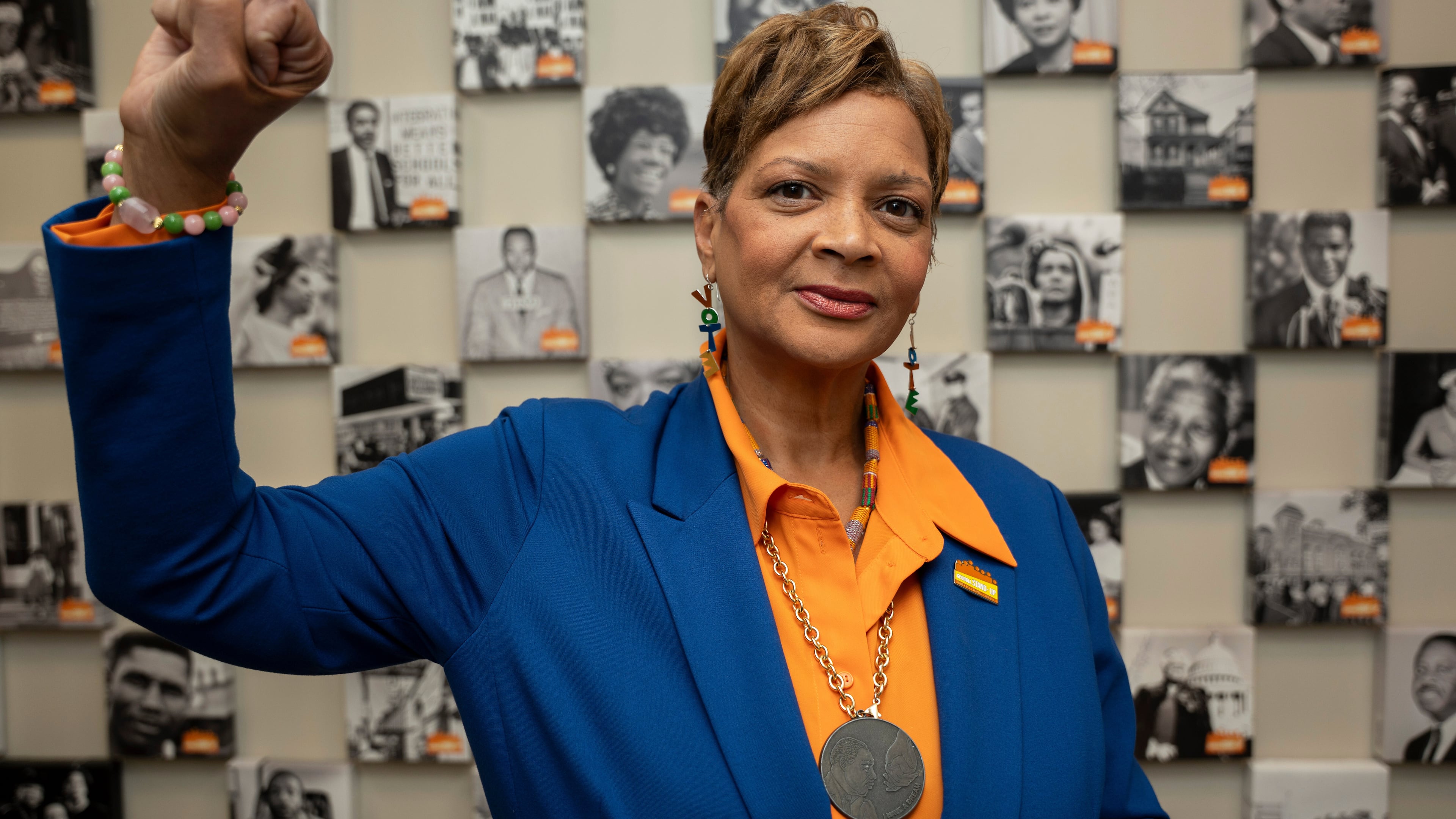 Deborah Scott, CEO of Georgia Stand-Up, raises her fist while standing in front of a wall honoring unsung heroes of the civil rights movement at The Movement Center, in Atlanta, Sunday, Nov. 30, 2025. (AP Photo/Olivia Bowdoin)