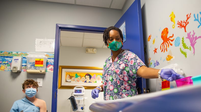 DeKalb Pediatric Center medical assistant Pheona Mack, right, administers Fred Kane, 16, his second dose of the Pfizer vaccination Thursday. The office expects long lines for the first week when 15-year-olds and younger become are eligible for covid vaccines. (Jenni Girtman for The Atlanta Journal-Constitution)