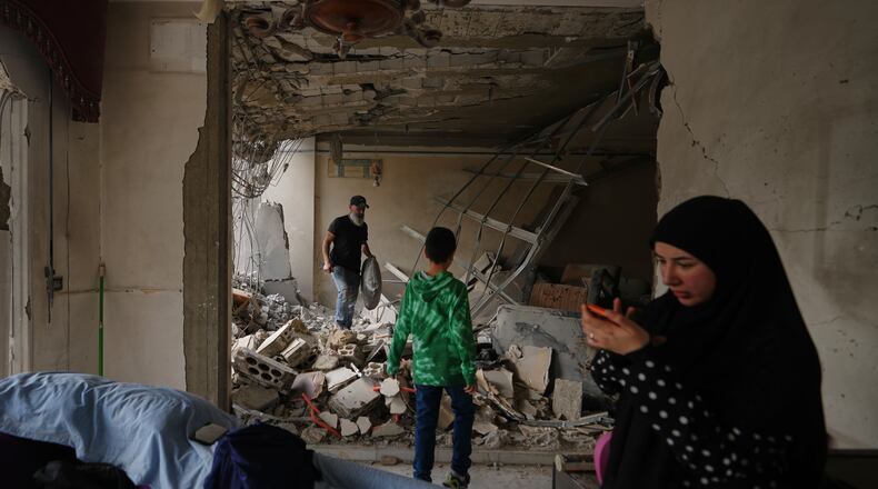 Fadi Al Zein, left, who lost both his homes in Israeli strikes in his village of Khiam and in Dahiyeh, searches through the rubble of his heavily damaged home as a child stands nearby, in Beirut's southern suburbs, Lebanon, Saturday, April 25, 2026. (AP Photo/Hassan Ammar)