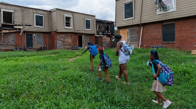 A family living in the Forest Cove Apartments walks to their home from the children's bus stop in August 2022. Atlanta completed the relocation of the condemned complex's residents in October of that year. (Arvin Temkar/The Atlanta Journal-Constitution/TNS)