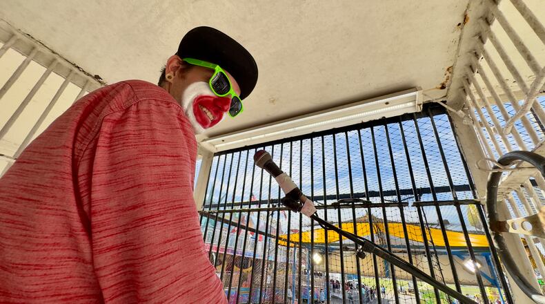 In his cage overlooking the midway, Justin Smith, a dunking-booth clown at the Georgia National Fair, barks quips at fairgoers via loudspeakers. (Joe Kovac Jr./AJC)
