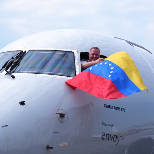 Capt. Ric Wilson waves a Venezuelan flag and the first officer waves a U.S. flag as they prepare to fly American Airlines Flight AA3599, the first direct commercial flight between the United States and Venezuela in seven years, Thursday, April 30, 2026, at Miami International Airport in Miami. (AP Photo/Rebecca Blackwell)