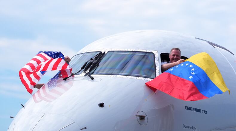 Capt. Ric Wilson waves a Venezuelan flag and the first officer waves a U.S. flag as they prepare to fly American Airlines Flight AA3599, the first direct commercial flight between the United States and Venezuela in seven years, Thursday, April 30, 2026, at Miami International Airport in Miami. (AP Photo/Rebecca Blackwell)